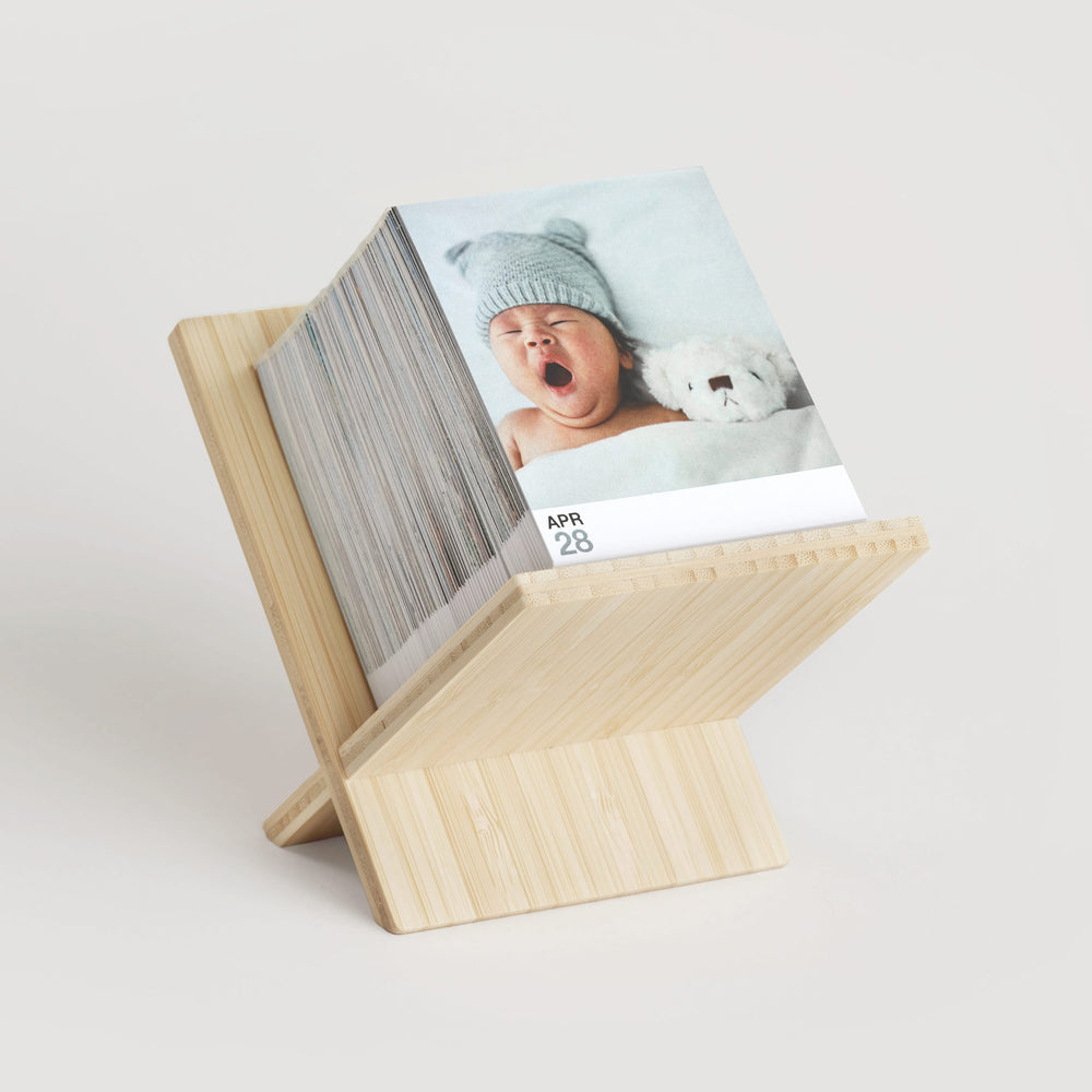 Daily Calendar with 365 photos featuring a cute baby photo. Placed on bamboo stand.